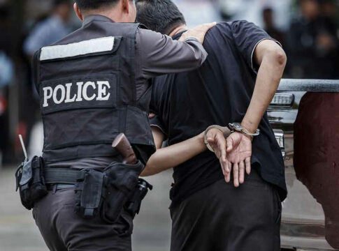 Police officer arresting a person in handcuffs.