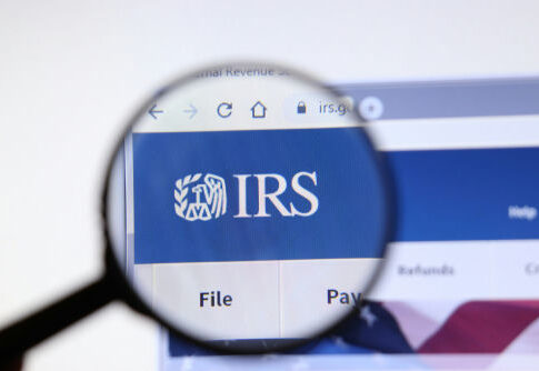 Magnifying glass over IRS website logo.