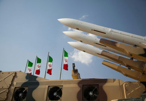 Military missiles displayed with Iranian flags in the background
