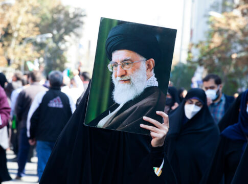 Person holding a large portrait in a crowd