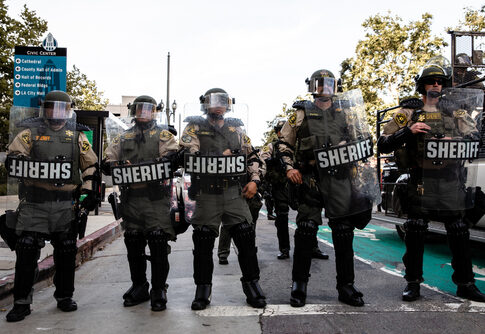 Sheriff deputies in riot gear standing in formation during a protest